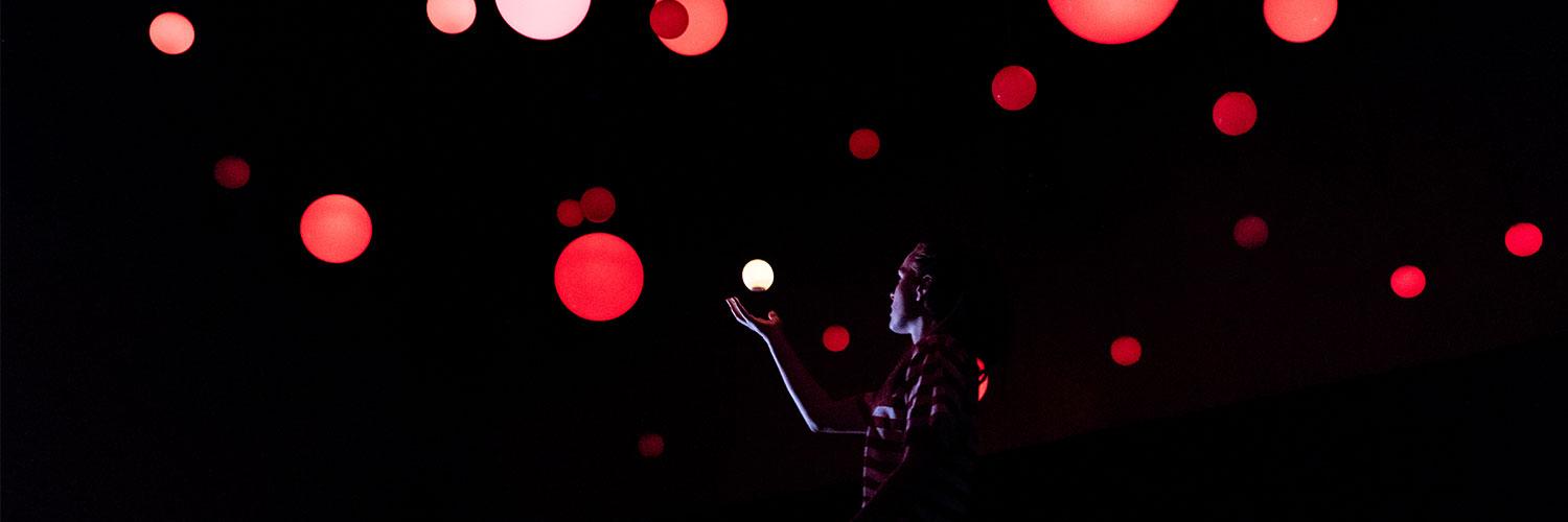 man in the darkness surrounded by red spotlights 