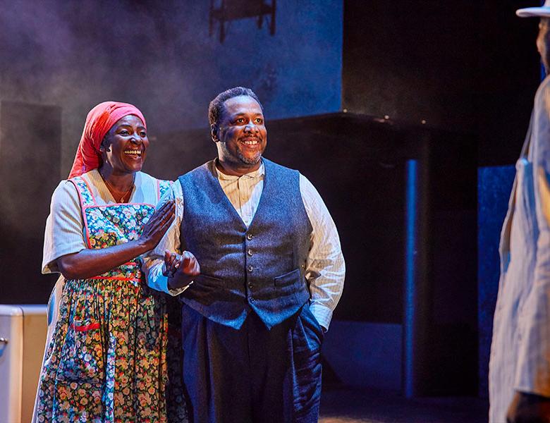 Sharon D. Clarke as Linda Loman and Wendell Pierce as Willy Loman stand together smiling and holding hands. 