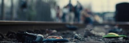 Shot from YV Short Film, Astoria. You can see a mix of abandoned shoes strewn along rail tracks, with out of focus figures slowly walking towards the camera.